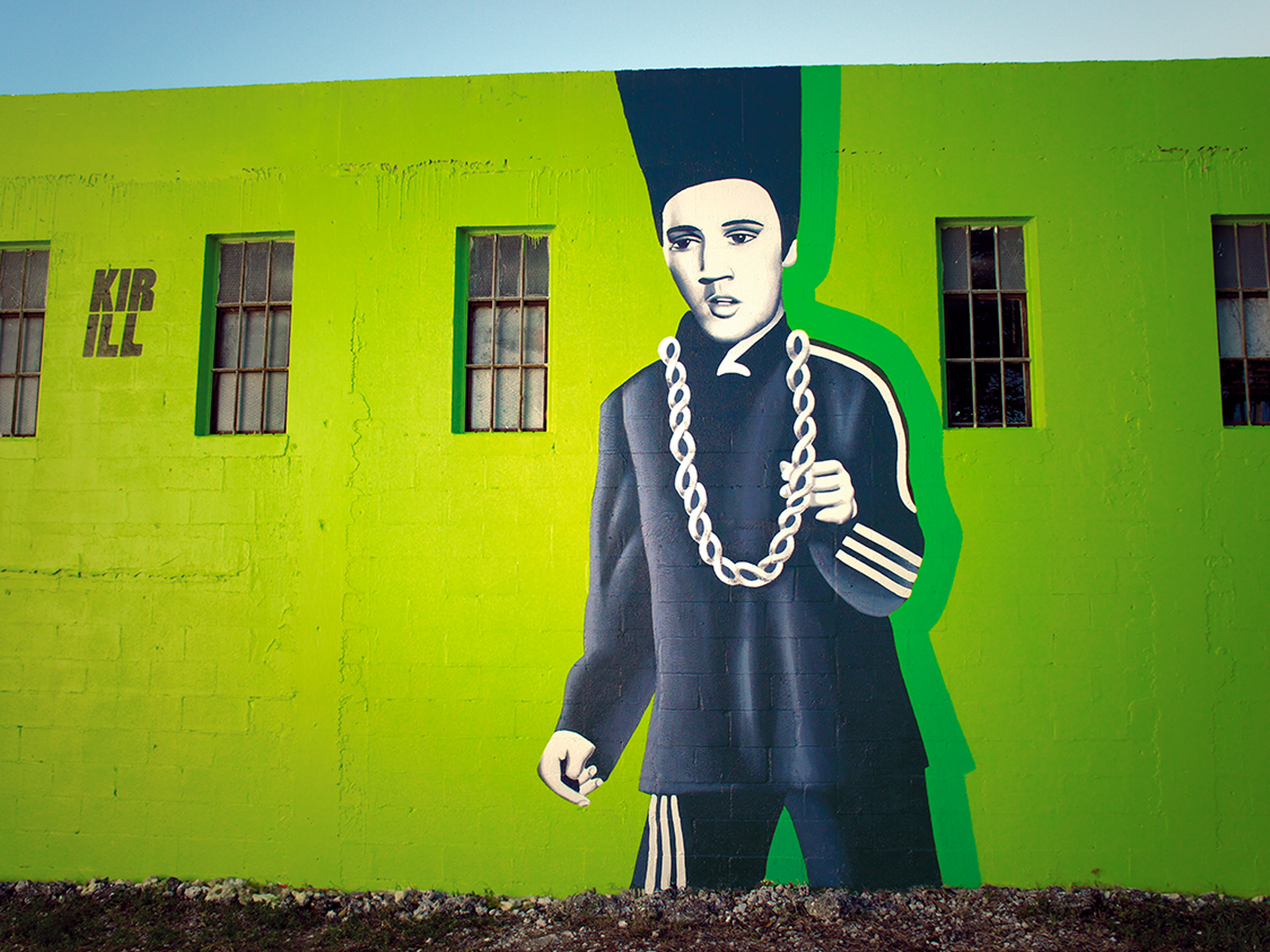 Bright green mural depicting a stylized person in dark clothing with a large white chain necklace, on a lime wall with windows nearby