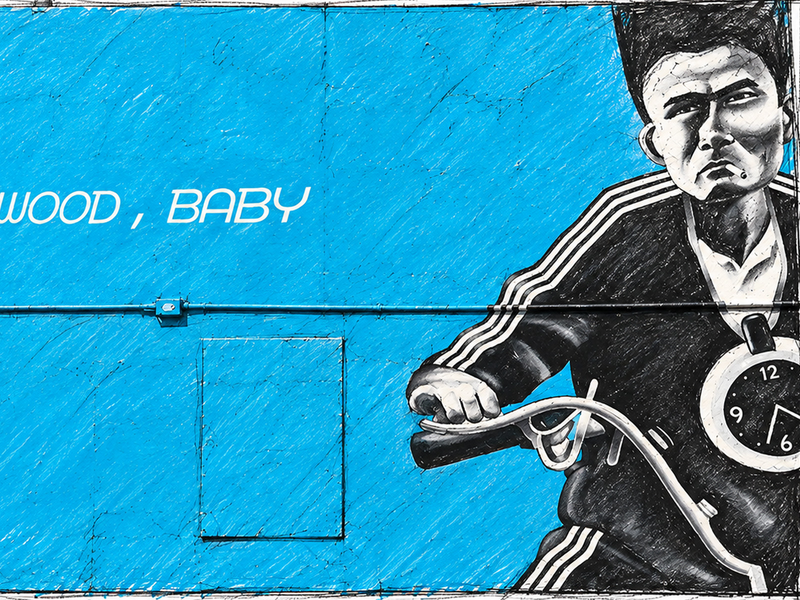 Blue wall mural featuring a stylized man in a black Adidas-style tracksuit, holding bike handlebars with a stopwatch, cigarette in mouth; text 'WOOD, BABY' partially visible.